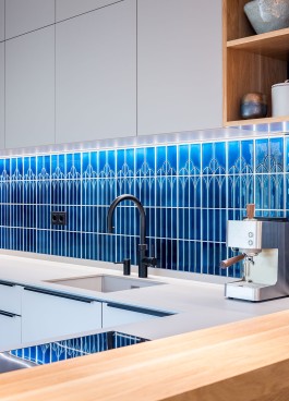 Innenarchitektur Wohnung - moderne Küche mit blauen Designfliesen, grauen Fronten und Eichenholz 