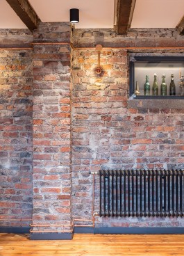 Innenarchitektur Design Brauerei Grohe Backsteinwand Schwarzstahlvitrinen Kupferrohre 