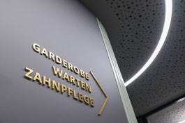 Innenarchitektur Zahnarztpraxis Darmstadt - Detailblick auf Messingschriftzug und gebogene Lichtlinie 